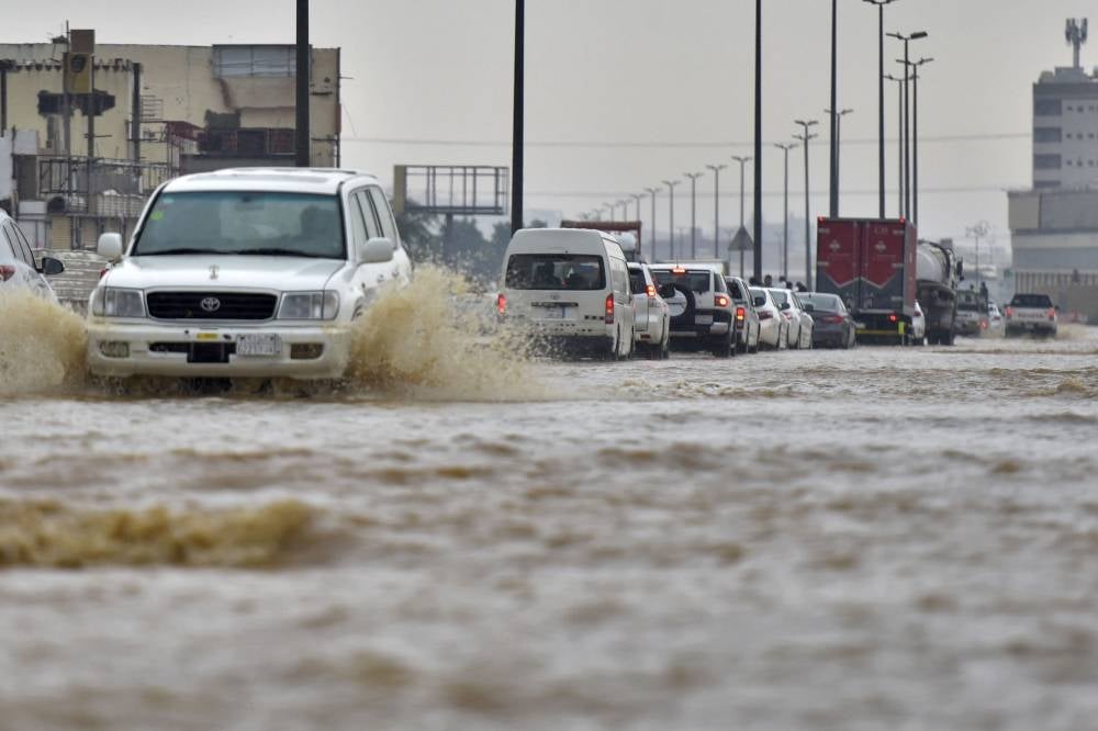 Cars drive through a flooded street following heavy rains in the Saudi coastal city of Jeddah on November 24, 2022, which delayed flights, forced school suspensions and closed the road to Mecca, Islam's holiest city. Photo by Amer Hilabi/AFP