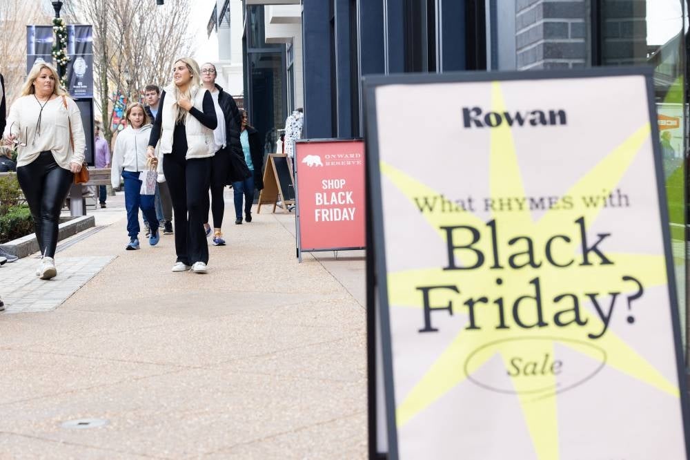 Shoppers walk past sale signs in the outdoor shopping area of Avalon during Black Friday on November 25, 2022 in Alpharetta, Georgia. Photo by Jessica McGowan/AFP.