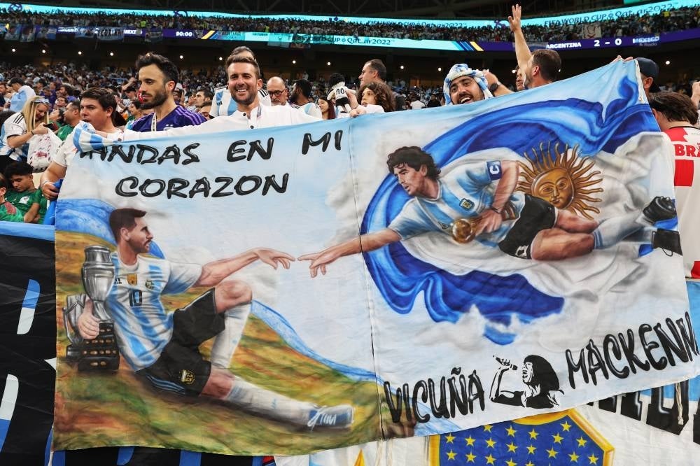 epa10331316 Fans of Argentina hold a banner depicting Lionel Messi (L) and Diego Maradona (R) in the manner of Michelangelo's painting 'The Creation of Adam' during the FIFA World Cup 2022 group C soccer match between Argentina and Mexico at Lusail Stadium in Lusail, Qatar, 26 November 2022. EPA/Mohamed Messara