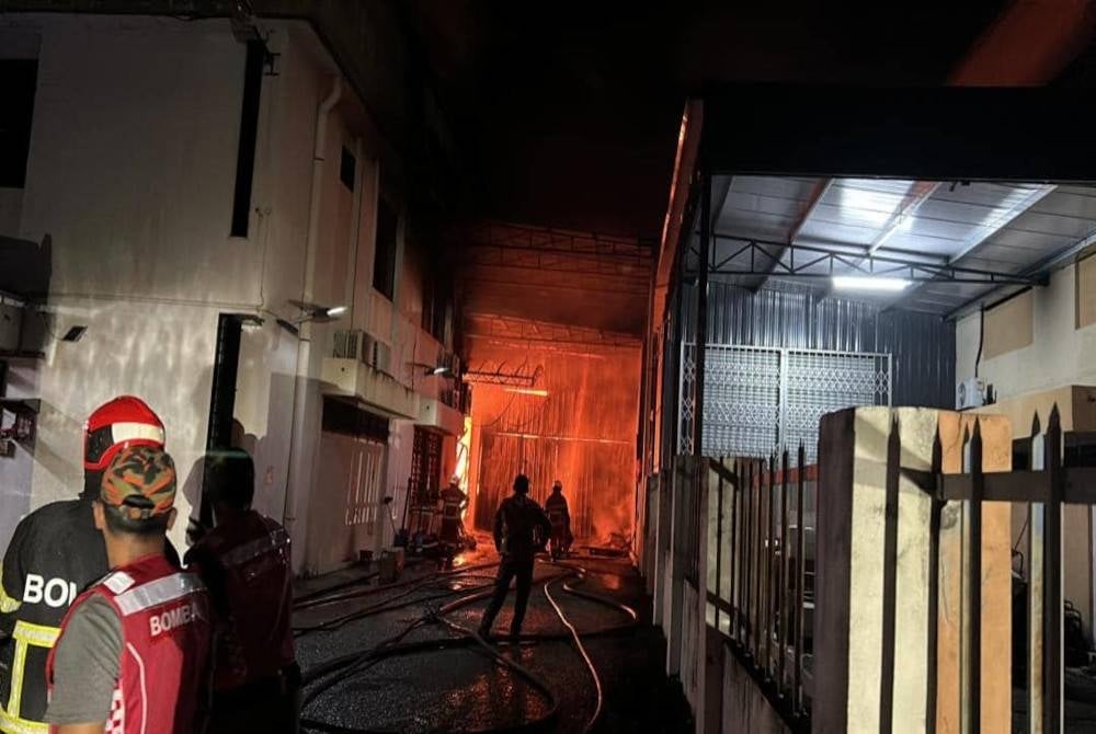 Firefighters while carrying out fire extinguishing work at four factories in Taman Perindustrian Puchong here on Sunday.