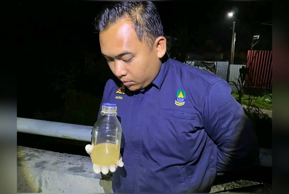 One of the LUAS staff smelled a water sample to detect odour pollution at Kampung Rinching Hilir in Sungai Semenyih on Thursday. - Photo: Sinar Archive