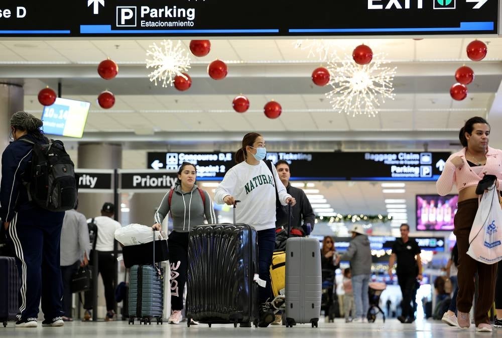  Travelers walk through Miami International Airport on Dec 19, 2022 in Miami, Florida. (Photo by JOE RAEDLE / AFP)