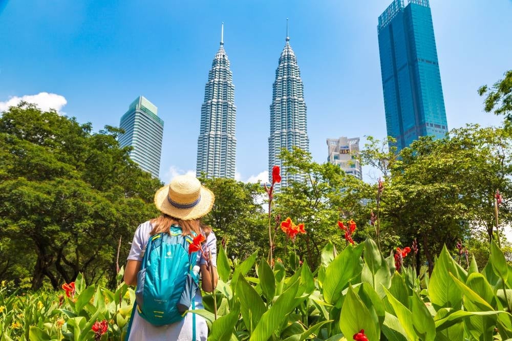 KUALA LUMPUR, MALAYSIA - FEBRUARY 25, 2020: Woman traveler at Petronas Tower in a sunny day in Kuala Lumpur, Malaysia
