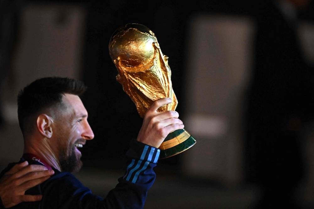 Argentina's captain and forward Lionel Messi holds the FIFA World Cup Trophy upon arrival at Ezeiza International Airport after winning the Qatar 2022 World Cup tournament on Dec 20, 2022. (Photo by LUIS ROBAYO / AFP)
