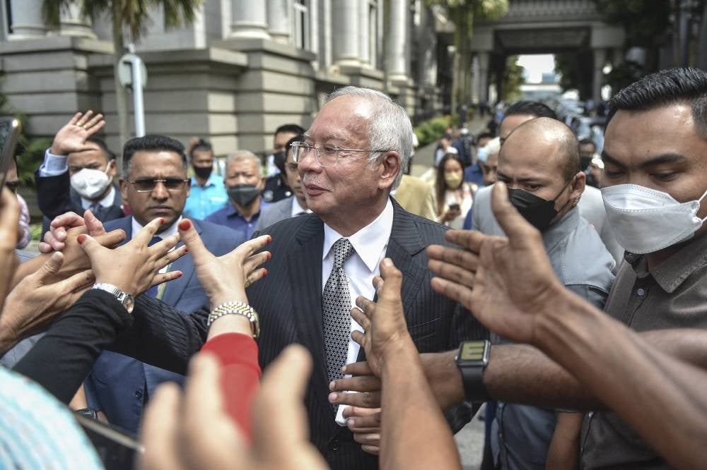 Former prime minister Datuk Seri Najib Razak greets supporters as he walks out during a break in the hearing of his appeal against his corruption conviction over the 1MDB financial scandal at the Federal Court on Aug 23, 2022. - (Photo by ARIF KARTONO/ AFP)