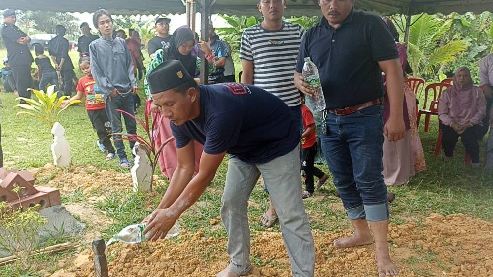 Ruslan sprinkled water on Luqman's grave after he was safely buried in Sungai Gatom Islamic Cemetery on Wednesday.