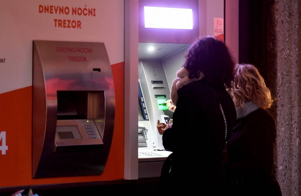 Clients withdraw cash at a bank in the center of Zagreb on December 30, 2022, as EURO becomes Croatia's official currency on Jan 1, 2023. (Photo by Denis LOVROVIC / AFP)