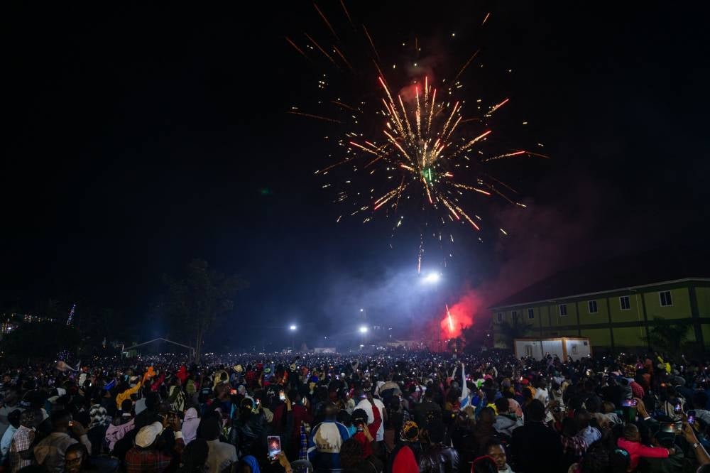 Fireworks light up the sky as people react while they celebrate after counting down to the new year at Miracle Centre Cathedral in Kampala, Uganda, on Jan 1, 2023. - (Photo by BADRU KATUMBA / AFP)