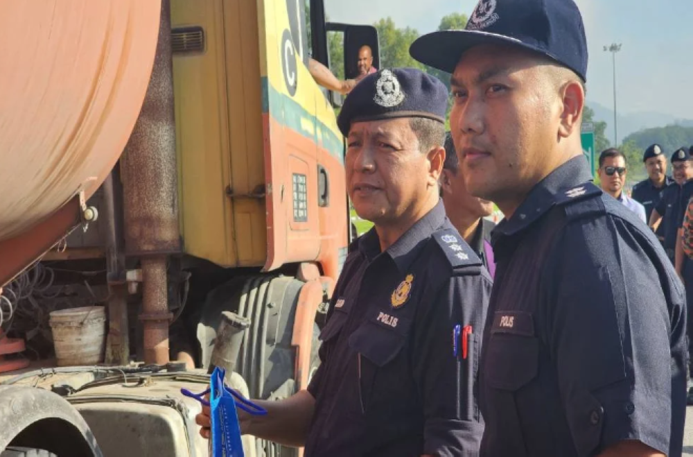 Mohd Zaid (left) giving out souvenirs to road users in conjunction with the 19th Op Selamat.