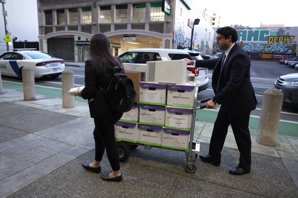 Legal aides move boxes of material as they arrive for the Elon Musk shareholder lawsuit trial at the Phillip Burton Federal Building on Jan 17, 2023 in San Francisco, California. - AFP