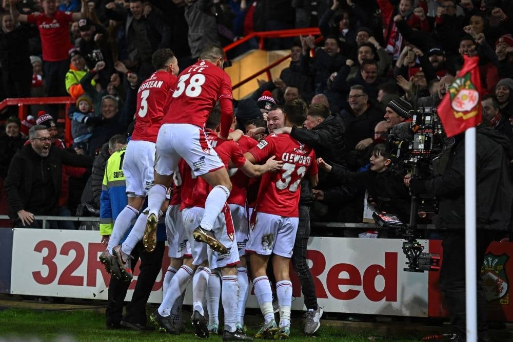 Wrexham's Irish midfielder Thomas O'Connor is mobbed by teammates after scoring the team's second goal during the English FA Cup fourth round football match between Wrexham and Sheffield United at the Racecourse Ground Stadium in Wrexham, north Wales, on Jan 29. - AFP