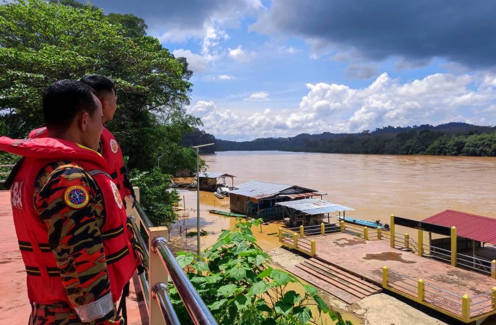 Firemen monitoring the water level at Kelantan river. Photo by Bernama.