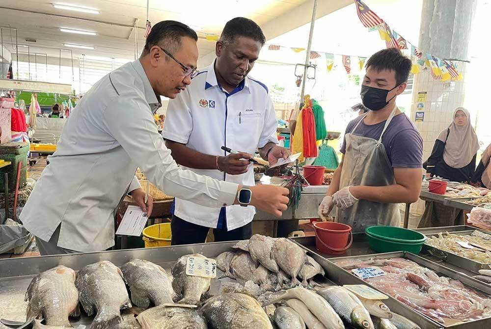 Jegan (second from the left) observing prices of fish at the Bayan Baru Public Market today.