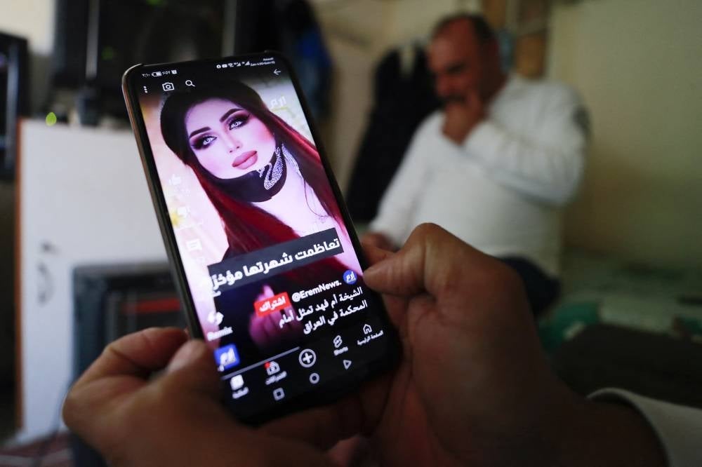 An iraqi man shows a post on a social media platform on Feb 12, 2023 in the capital Baghdad, with a picture of TikTok celebrity Om Fahad, announcing that she has been jailed by the authorities. - AFP