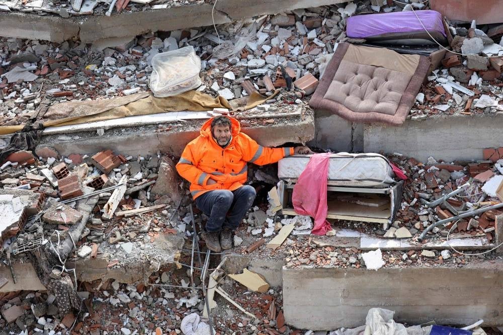 Mesut Hancer holds the hand of his 15-year-old daughter Irmak, who died in the earthquake in Kahramanmaras, close to the quake's epicentre, the day after a 7.8-magnitude earthquake struck the country's southeast, on Feb 7, 2023. - (Photo by ADEM ALTAN / AFP)