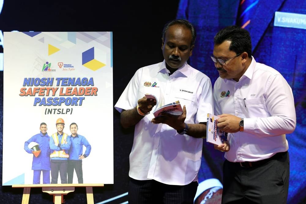 Human Resources Minister V Sivakumar (left) has a look at the NIOSH-Tenaga Safety Leader Passport (NTSLP) book during a partner appreciation ceremony at the National Institute for Organisational Safety and Health (NIOSH) today. - Photo: BERNAMA