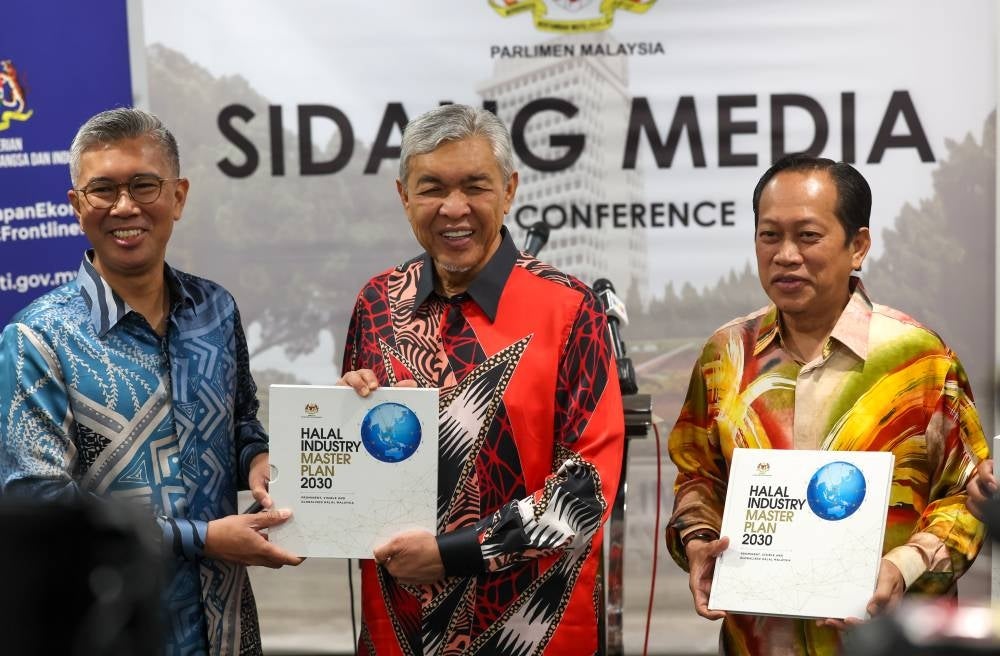 Deputy Prime Minister Datuk Seri Ahmad Zahid Hamidi (middle) with International Trade and Industry Minister Tengku Datuk Seri Zafrul Tengku Abdul Aziz (left) and Deputy Finance Minister Datuk Seri Ahmad Maslan showing the Halal Industry Master Plan 2030 (HIMP 2030) during its launching at the Parliament, today. - BERNAMA