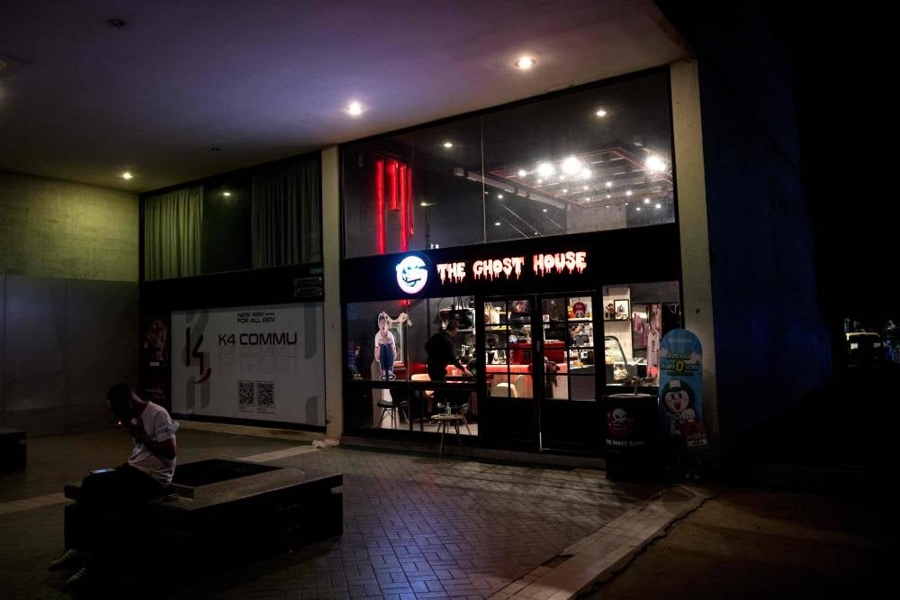 In this photo taken on March 25, a man smokes a cigarette outside the Ghost House cafe, owned by Ghost Radio station host Jack Watcharaphonat, in Bangkok. - Pic: AFP