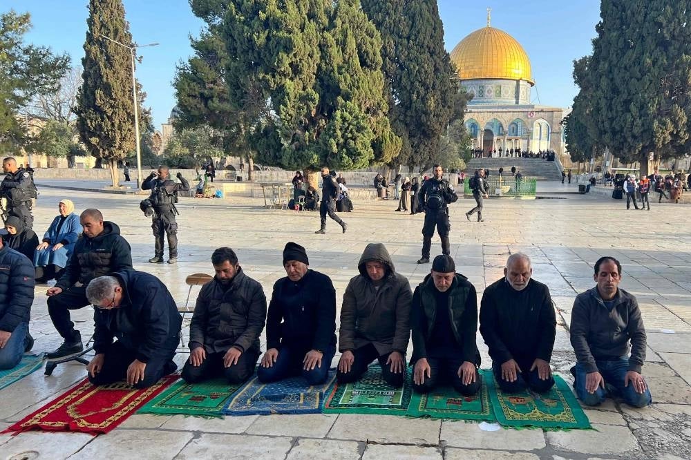 Israeli security forces stand guard as Palestinians pray in Jerusalem's al-Aqsa Mosque compound on April 5, 2023 during the Muslim holy month of Ramadan. - Israeli police in riot gear stormed the mosque's prayer hall before dawn, with the goal of dislodging "law-breaking youths and masked agitators" who they said had barricaded themselves inside following evening prayers - AFP 