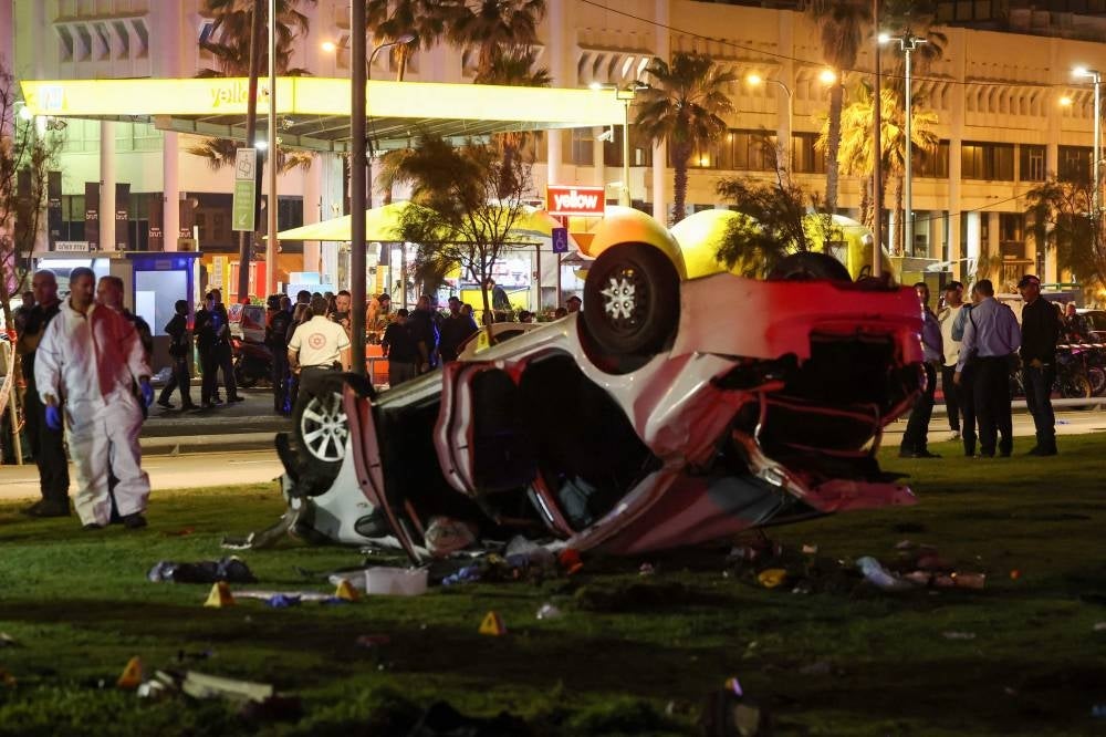 Israeli police gather next to a car used in a ramming attack in Tel Aviv on April 7, 2023. - One man was killed and four people were wounded in an attack in central Tel Aviv, Israeli rescue services said, updating a previous casualty toll of two injured - AFP