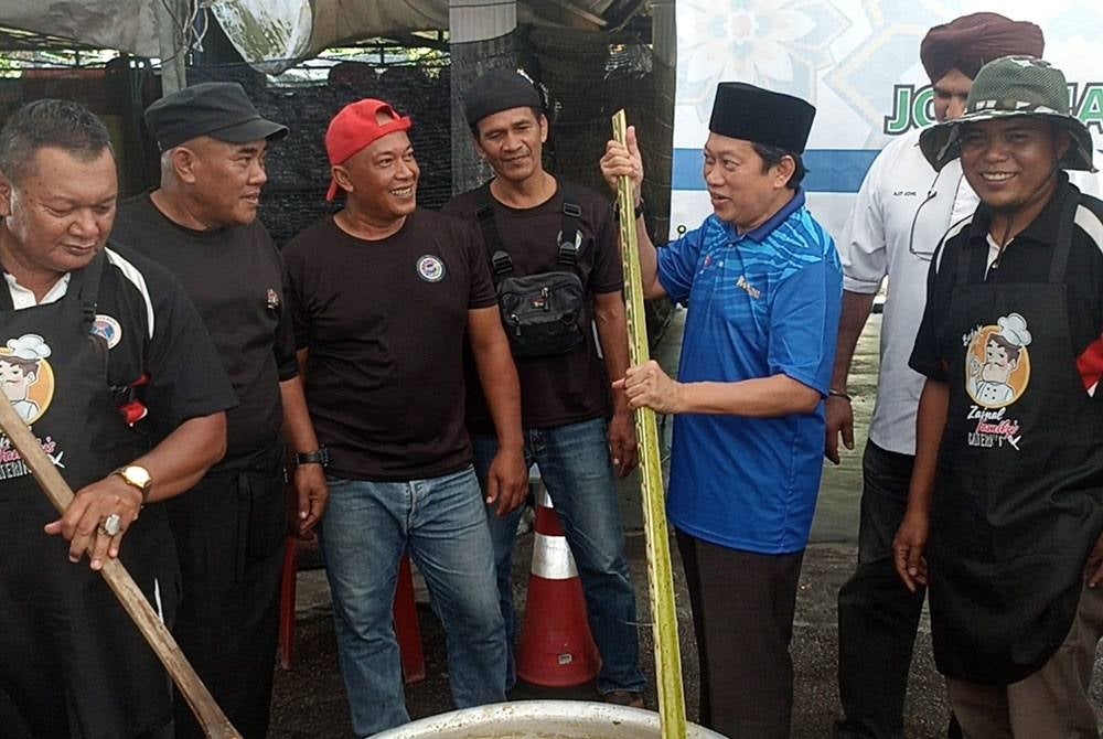 Ahmad (second from right) stirs the bubur lambuk with the community in Ayer Baloi on Saturday.