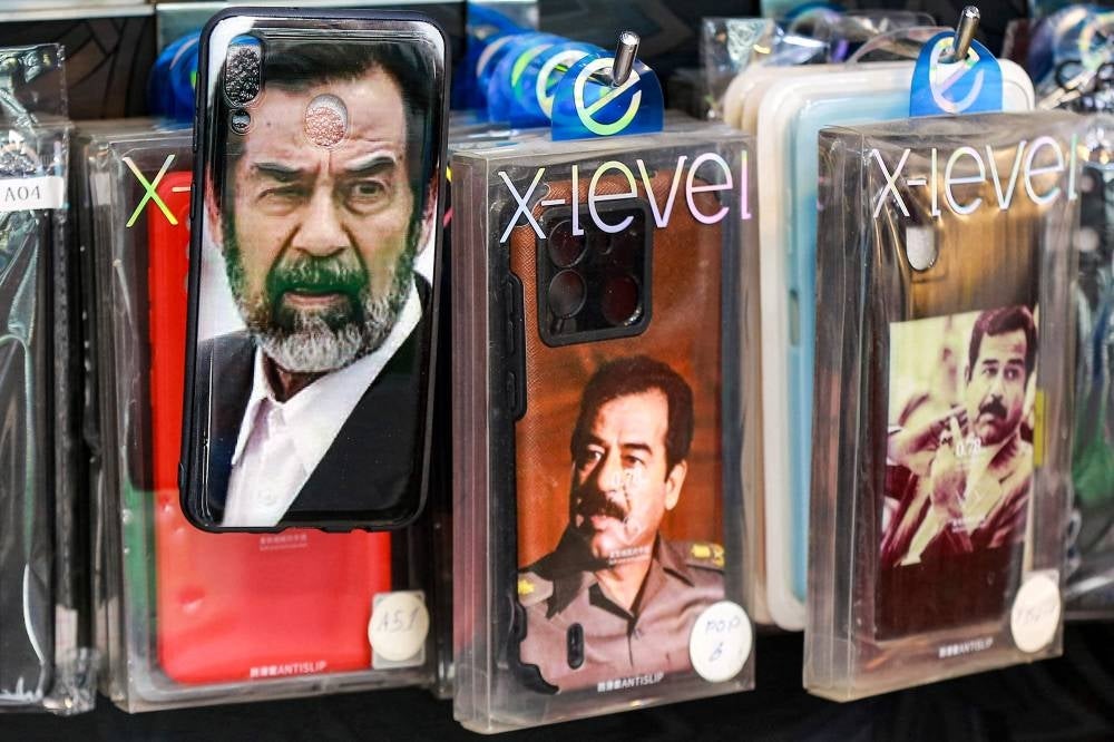 Cell phone covers showing the image of Iraq's late ousted dictator Saddam Hussein are displayed with others at a shop in Amman. - Twenty years after the fall of his regime, the late Iraqi president Saddam Hussein remains admired and popular in Jordan where his image can still be seen across the country. The instantly recognisable face peers out from car stickers to mobile phone covers in Jordan, despite symbols and images associated with his rule being widely considered taboo in Iraq itself. - Pic: AFP
