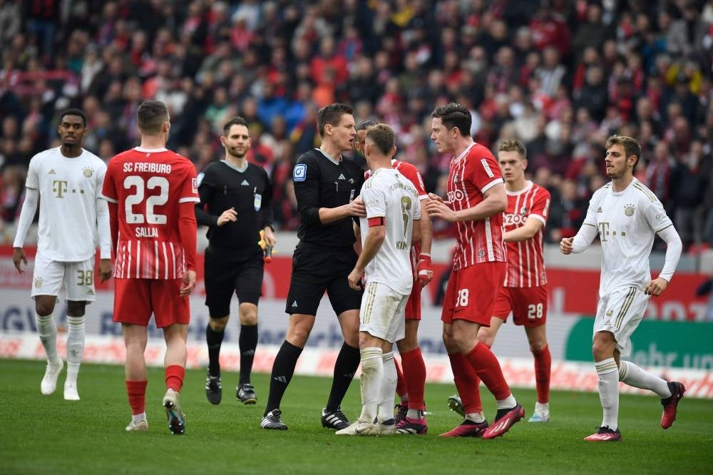 The referee has word with Bayern Munich's German midfielder Joshua Kimmich and Freiburg's Austrian forward Michael Gregoritsch during the German first division Bundesliga football match between SC Freiburg and Bayern Munich in Freiburg on April 8. - Pic: AFP