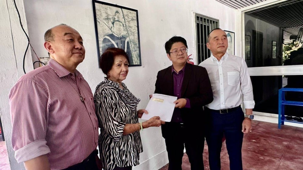 Ewon (second from right) presented a copy of the Double Six plane crash tragedy final report to Nancy. She was accompanied by her son Donald (right) at their home in Kampung Hungap, Penampang.