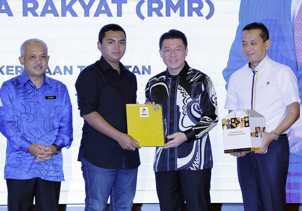 Local Government Development Minister Nga Kor Ming (second from right) presenting an offer letter to Muhammad Amirul Haziq Mohamad Azmi (second from left) at the RMR Offer Letter & Key Handover Ceremony in Putrajaya on Thursday - BERNAMA