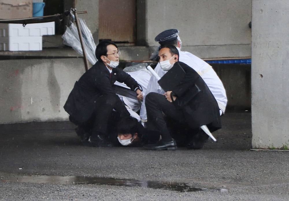 A man (bottom) is arrested after throwing what appeared to be a smoke bomb in Wakayama on April 15, 2023. - Japanese Prime Minister Fumio Kishida was evacuated from a port in Wakayama after a blast was heard, but he was unharmed in the incident - AFP 