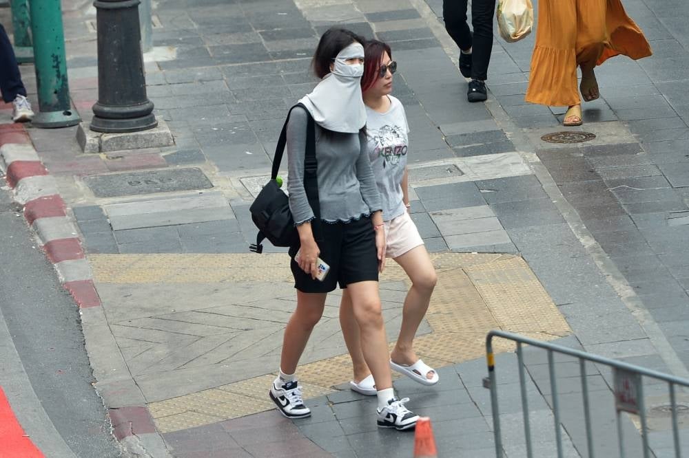 A pedestrian shades herself from sunshine with a face mask in Bangkok, Thailand, April 19. Thailand experienced continuous high temperature recently, with the highest temperature in many provinces exceeding 40 degrees Celsius. The Ministry of Public Health of Thailand reminded the public to reduce outdoor activities. - Pic: XINHUA