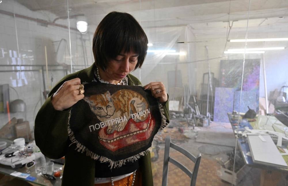 Ukrainian artist Zhanna Kadyrova shows her creation with signing "Air raid alert" in her workshop in Kyiv on April 26. - When Russia invaded Ukraine, artist Zhanna Kadyrova felt her work was useless. But the 42-year-old changed her mind as galleries around the world snapped up her war-inspired work, raising funds to help civilians and soldiers. - Pic: AFP