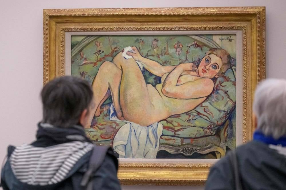 Visitors look at the painting titled 