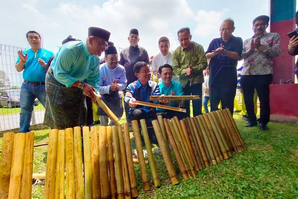 Kon Yeow (seated, left) opening the lemang at the Batu Kawan Parliament Aidilfitri Open House and Bukit Tambun State Legislative Assembly Constituency in Taman Tangling on Saturday.