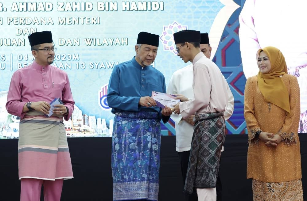 Deputy Prime Minister and Rural and Regional Development Minister Datuk Seri Ahmad Zahid Hamidi (two, left) presenting contributions TO students of MRSM Kota Kinabalu. - BERNAMA