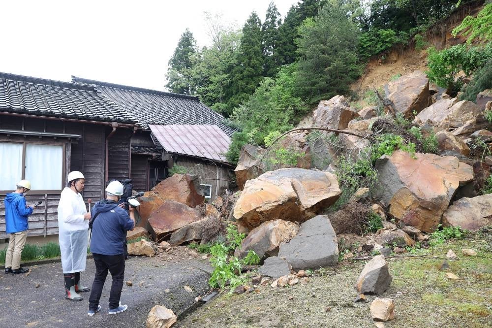 Large boulders sit at the back of a house where a woman was trapped after a landslide was triggered by a 6.5 magnitude earthquake in the area the day before, in the city of Suzu, Ishikawa prefecture on May 6, 2023. - AFP
