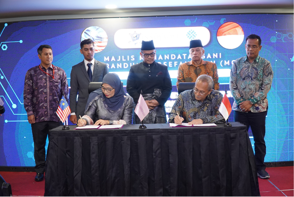 Shahawati Umar and Budi Hartawan signs the memorandum of understanding (MoU) document while witnessed by (L-R), Erga Grenaldi, Mohd Farha Md Ishak, Azizan Osman, Dr. Hashim Yaacob and Andri Susila at the Perdana Hotel, in Kuala Lumpur. .