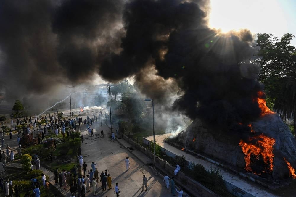 Black smoke billows from a street installation set alight during a protest by Pakistan Tehreek-e-Insaf (PTI) party activists and supporters of former Pakistan's Prime Minister Imran against the arrest of their leader, in Peshawar on May 9, 2023. (Photo by Abdul MAJEED / AFP)