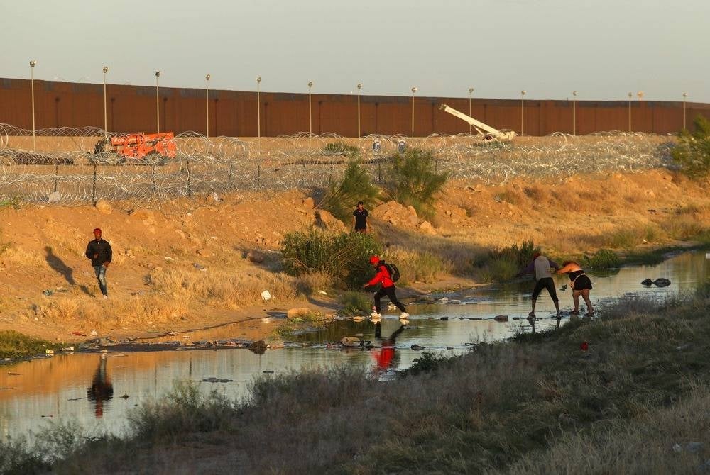 Migrants cross the Rio Grande River to surrender to Border Patrol agents from El Paso Sector after crossing from Ciudad Juarez, Chihuahua state, Mexico, on May 4, 2023. Under the intense desert sun, among sand and brush, hundreds of migrants crossed the Rio Grande from Mexico on the rumor that the United States would let them in. But their hopes were dashed as they fell prey, once again, to misinformation. Falsehoods and deceptions add to the ordeal of these people, first to reach the border through Mexico and then to obtain asylum in the United States. (Photo by HERIKA MARTINEZ / AFP)