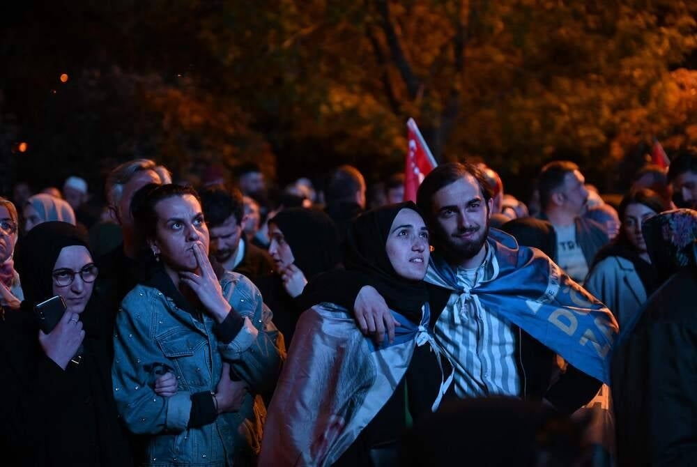 Supporters of Turkish President look at early presidential election results displayed on a screen of the Justice and development Party (AKP’s) headquarters after polls closed in Turkey's presidental and parliamentary elections, in Istanbul, on May 14, 2023. Turkish polling stations have closed in a knife-edge election that could end President Recep Tayyip Erdogan's two-decade grip on power and put the mostly Muslim nation on a more secular course. Turnout was expected to be huge in what has effectively become a referendum on Turkey's longest-serving leader and his Islamic-rooted party. (Photo by OZAN KOSE / AFP)