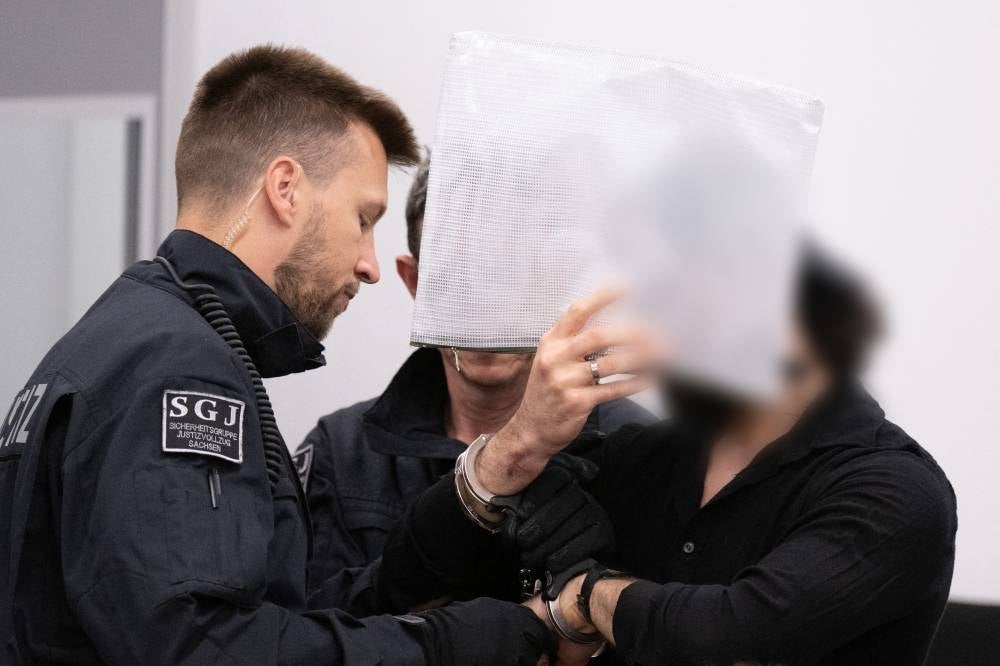 A defendant (R) is brought to the courtroom on May 16, 2023 at the Higher Regional Court in Dresden, eastern Germany, prior to a hearing in the trial over a jewellery heist on the Green Vault (Gruenes Gewoelbe) museum in Dresden's Royal Palace in November 2019. - AFP