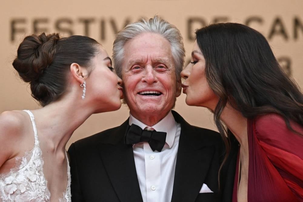 British actress Catherine Zeta-Jones (R) and her daughter Carys kiss US actor Michael Douglas on the cheek as they arrive for the opening ceremony and the screening of the film "Jeanne du Barry" during the 76th edition of the Cannes Film Festival in Cannes, southern France, on May 16, 2023. (Photo by LOIC VENANCE / AFP)