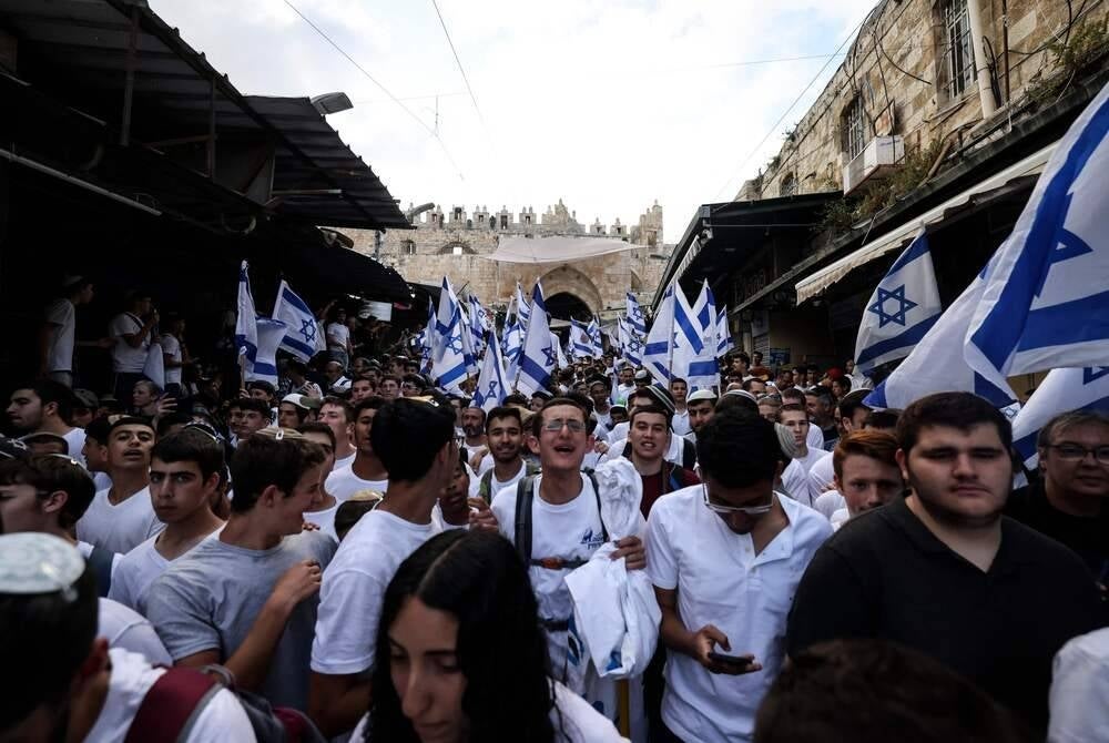 Israelis wave national flags as they enter the Old City of Jerusalem via Damascus Gate during the Israeli 'flags march' to mark "Jerusalem Day", on May 18, 2023. Jerusalem police and residents are bracing for extremist ministers and their supporters to rally on May 18 in an annual flag-waving march commemorating Israel's capture of the Old City. (Photo by HAZEM BADER / AFP)