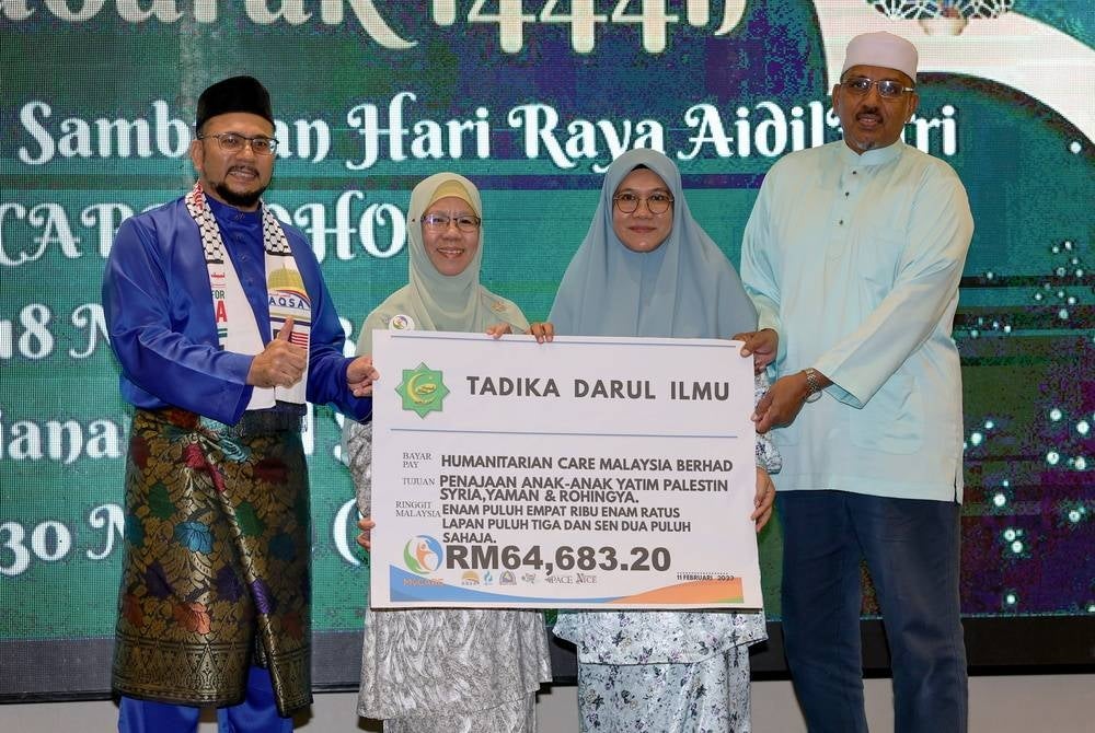 General Manager of MyCare Pusat Roha Hassan (left, second) receiving a replica of the donation cheque from the Founder and Manager of Tadika Darul Ilmu, Helena Hussin (right, second) and Mohd Hafidzuddin Raja Abdullah (right) at the MyCare Johor Aidilfitri Celebration at a hotel. - BERNAMA