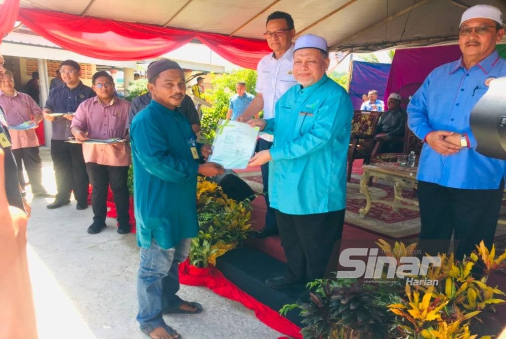 Nik Amar (two from right) awarding the land grant to residences at Tanah Merah - FILEPIC
