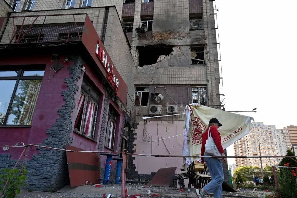 A local resident walks past a partially destroyed residential building after a massive Russian drones strike mainly targetting the Ukrainian capital, in Kyiv, on May 28, 2023. - (Photo by SERGEI SUPINSKY / AFP)