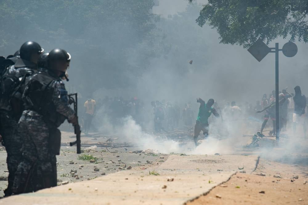 Supporters of opposition leader, Ousmane Sonko throw stones while police fire tear gas in Dakar on June 1, 2023, during unrest following the sentence of opponent Ousmane Sonko. Photo by Guy Peterson/AFP.