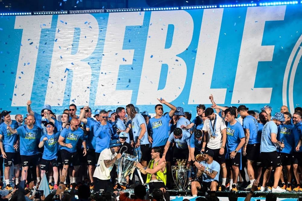 Manchester City's players celebrate on stage with their trophies following an open-top bus victory parade for their European Cup, FA Cup and Premier League victories, in Manchester, northern England on June 12, 2023. - Photo by AFP