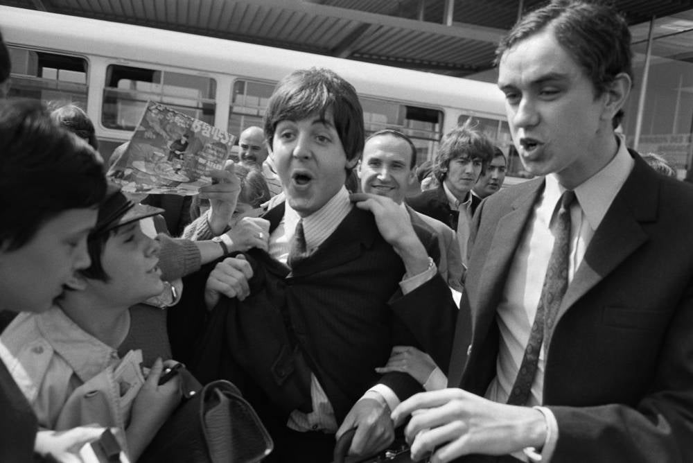 (FILES) Fans surround Beatles Paul McCartney (C) and George Harrison (2R) upon their arrival at Orly airport on June 20, 1965, before their concert at the Palais des Sports the same evening. - Photo by AFP