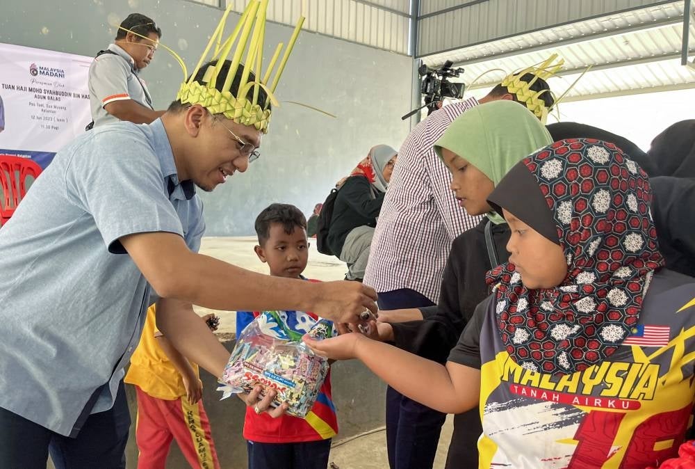 Kelantan Director of the Malaysian Information Department (JAPEN) Muhd ​​Nor Aswadi Md Nor (left) giving sweets to Orang Asli children of the Temiar tribe in conjunction with the Kita MADANI 2023 program at Pos Tuel today. Also present was State Assemblyman Galas Mohd Syahbuddin Hashim - BERNAMA